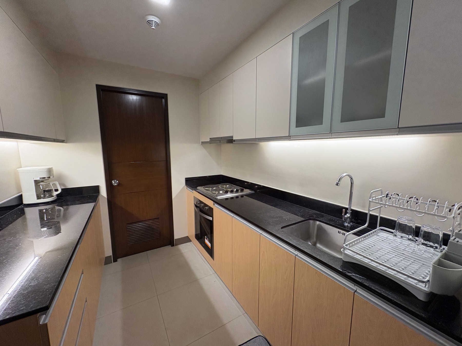 Galley kitchen in the DAYON TA condo, with a gas hob, oven, sink, and lit counters running the length of both walls